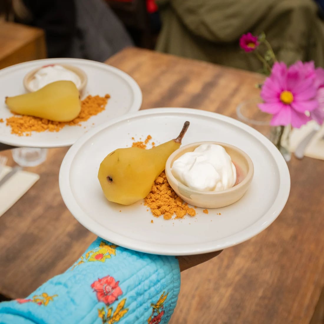A poached pear dessert beside a cosmos flower