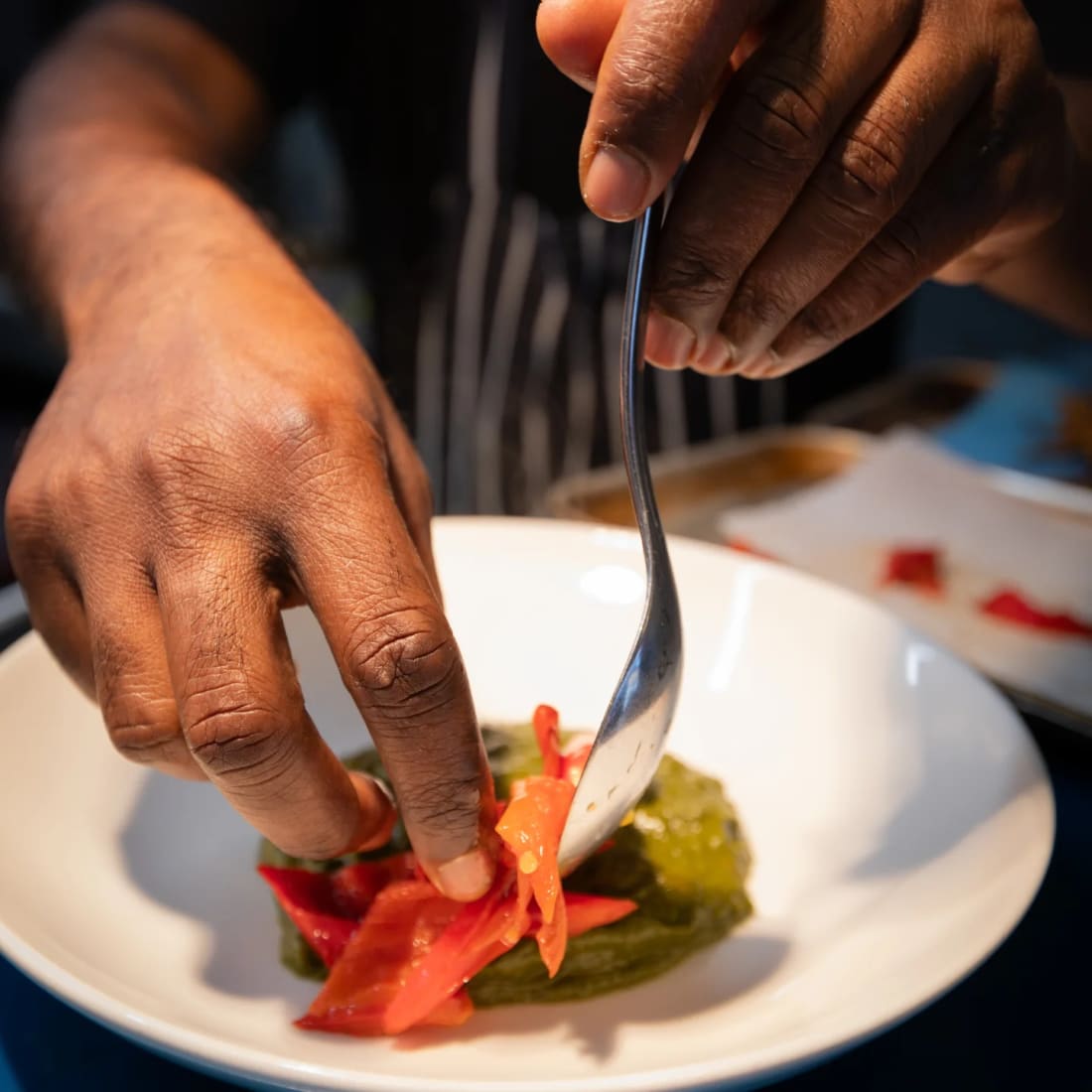 Chef Dhayalan's hands plating at the pass