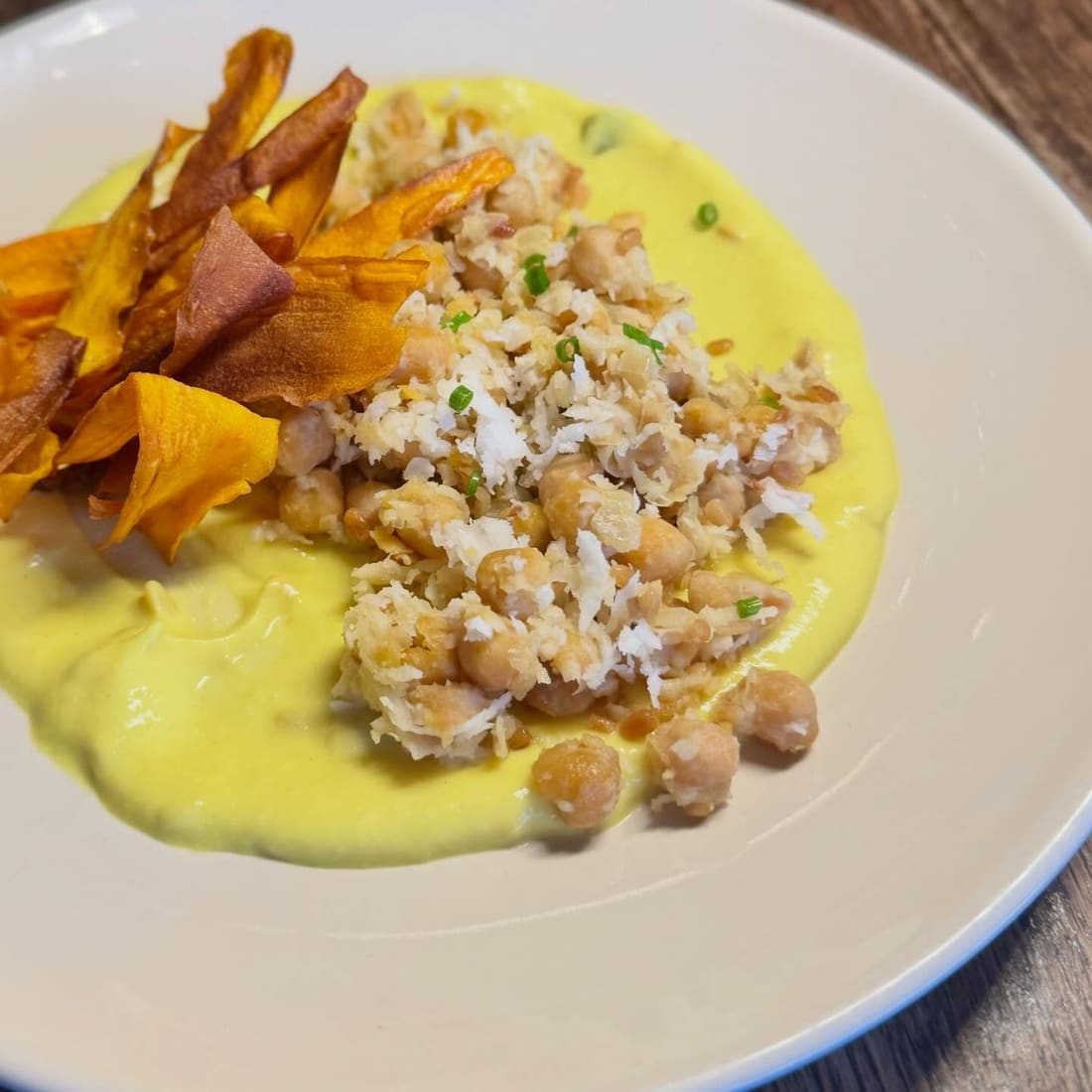 A plate over turmeric-yellow pachadi with sweet potato crisps
